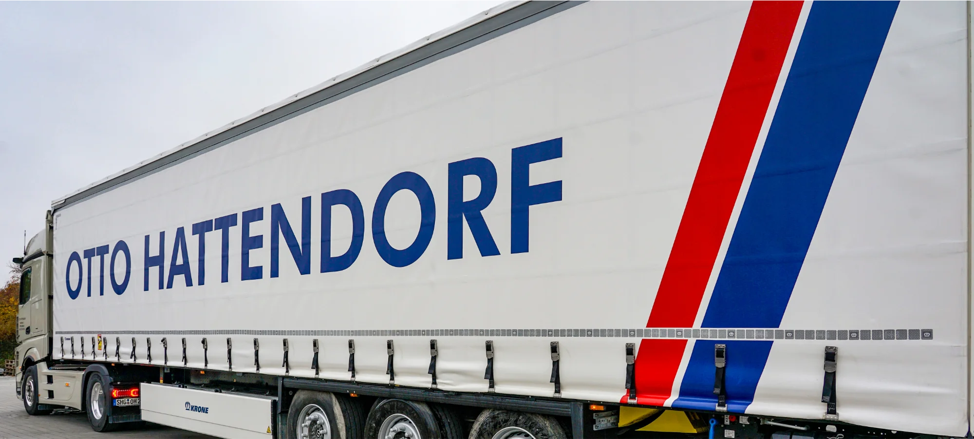 Planen LKW mit dem Otto Hattendorf Logo auf der Seitenplane, schräg von hinten aufgenommen